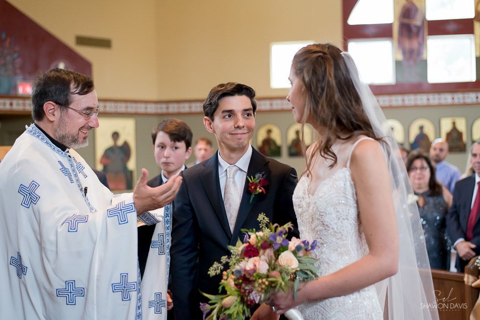Bride and groom at altar during a church wedding, with priest speaking nearby