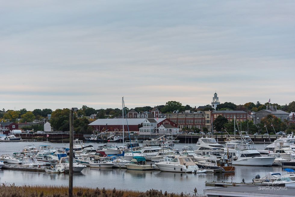 Marina packed with white yachts beside waterfront buildings under a cloudy sky