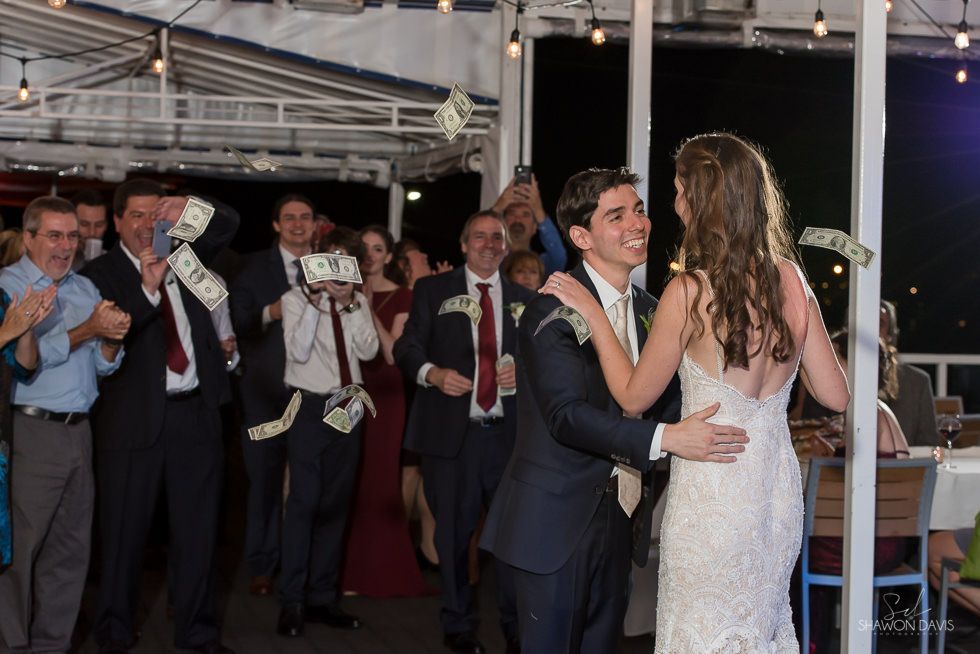 Bride and groom slow dance at a nighttime wedding reception while guests applaud nearby
