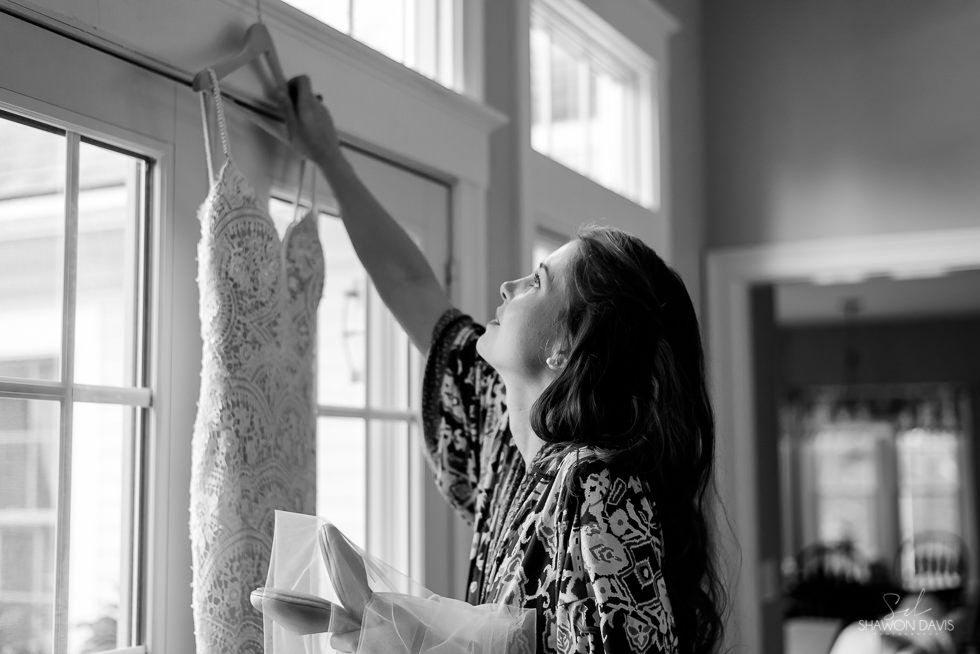 Woman hanging a dress by a window in a bright room