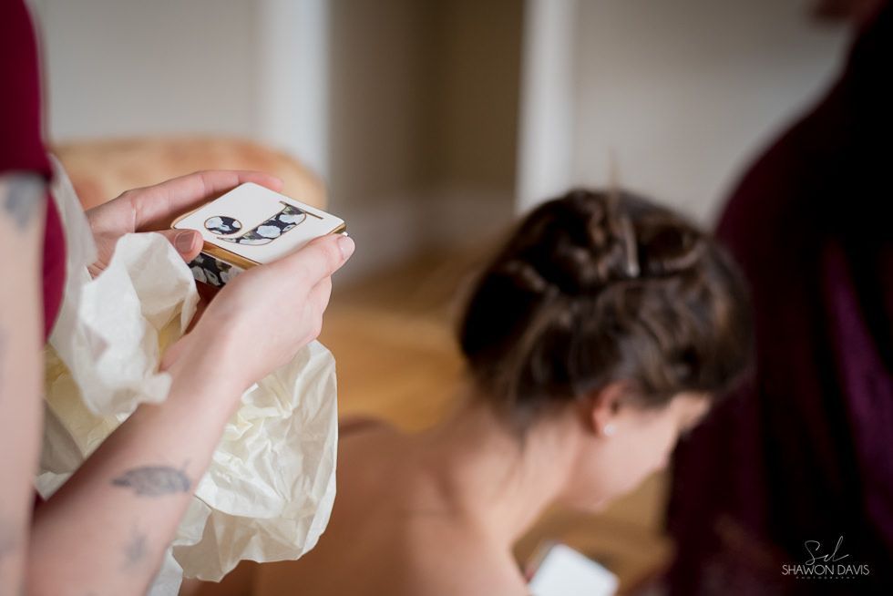Hands holding a small photo over a seated person with an updo hairstyle in a softly lit room