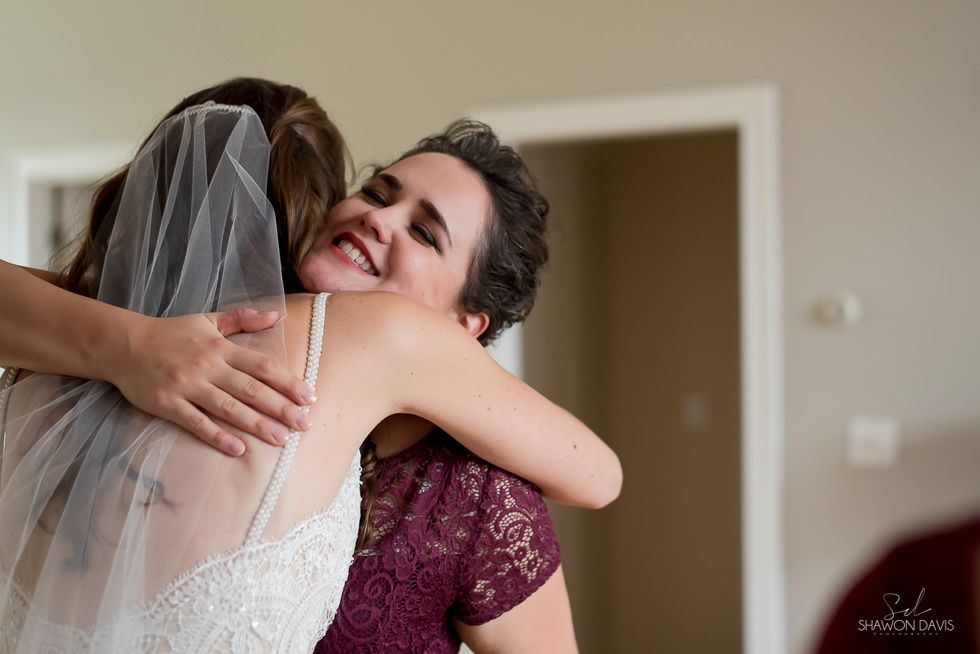 Bride hugging smiling guest indoors in a warmly lit room