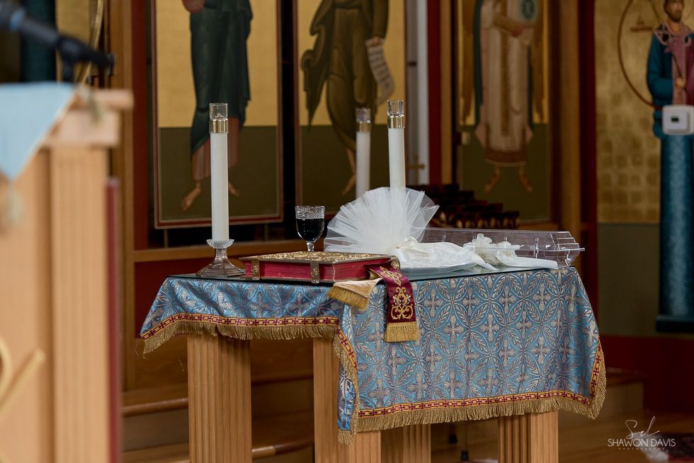 Altar table with white candles, folded cloth, and flowers in a church interior