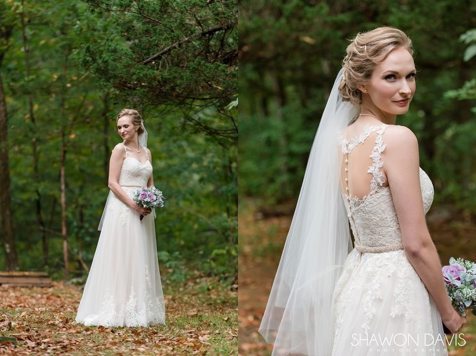 Bride in a white gown and veil holding a bouquet in a wooded outdoor setting