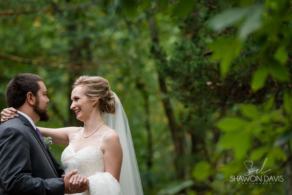 Bride and groom smiling at each other in a green garden wedding setting
