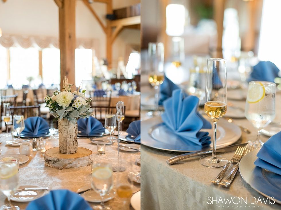 Elegant banquet table set with blue napkins, glassware, candles, and floral centerpieces in a bright venue