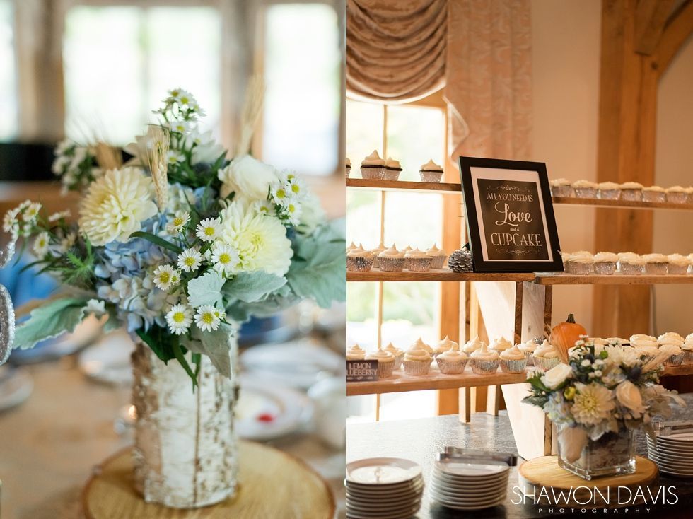 Elegant floral wedding display with white-and-blue bouquets, candles, and gold decor on a dessert table
