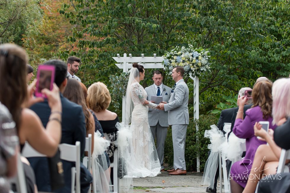 Wedding couple exchanging vows under floral arch in an outdoor garden ceremony