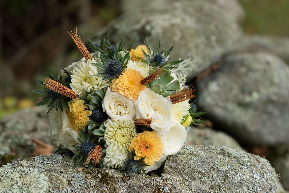 Bouquet of white and yellow flowers arranged on rough rocks outdoors