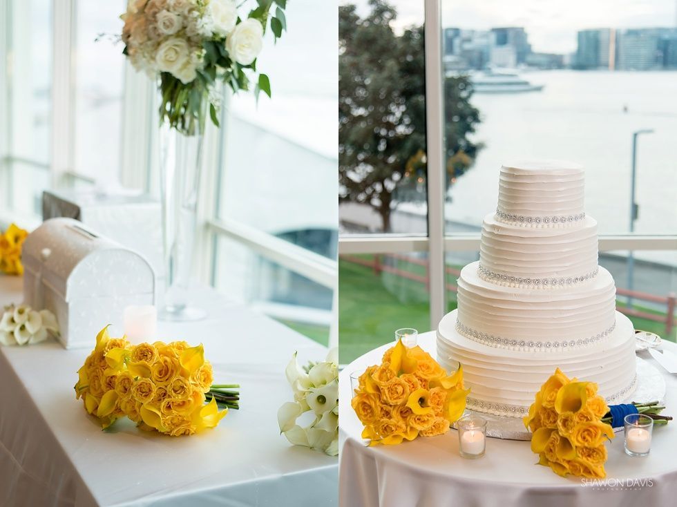 Wedding cake with yellow bouquets on a table by a bright waterfront window