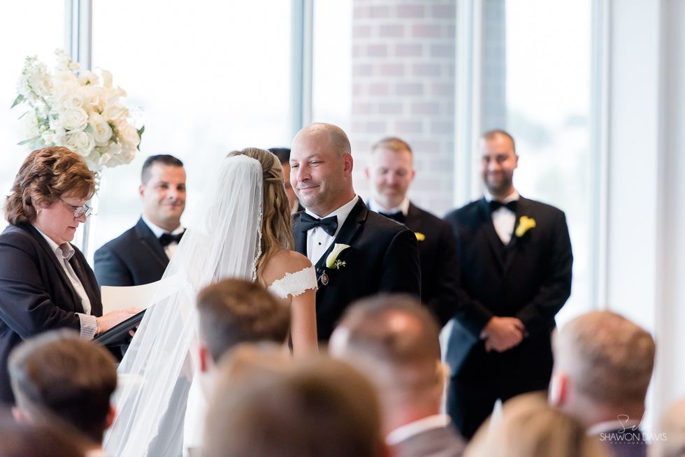 Wedding ceremony with bride and groom exchanging vows before officiant and guests in a bright venue