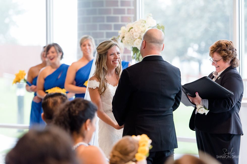 Wedding ceremony with bride and groom at the altar, bridesmaids in blue dresses standing nearby.