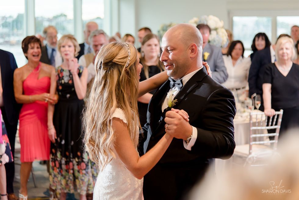 Couple dancing at a wedding reception, guests watching in the background.