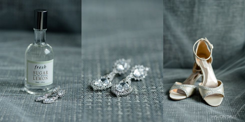 Perfume bottle, silver jewelry, and beige high heels on a gray fabric backdrop