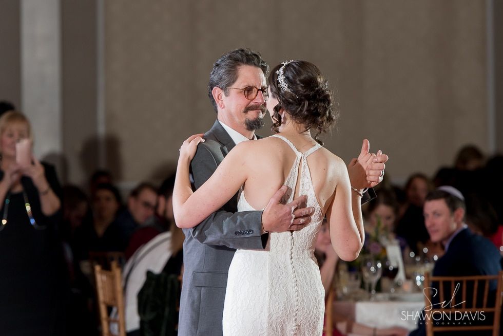 Couple slow dancing at a formal reception, with the bride in a white dress and groom in a dark suit