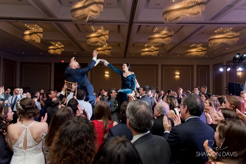 Wedding reception crowd cheering as two people dance and reach toward each other on a stage