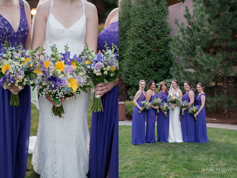 Bridesmaids in purple hold lavender and yellow bouquets beside the bride in a white dress on a lawn.