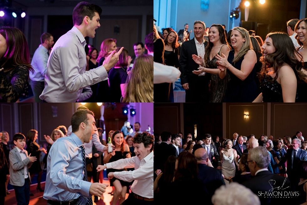 People chatting and laughing at a lively indoor event under colorful stage lighting