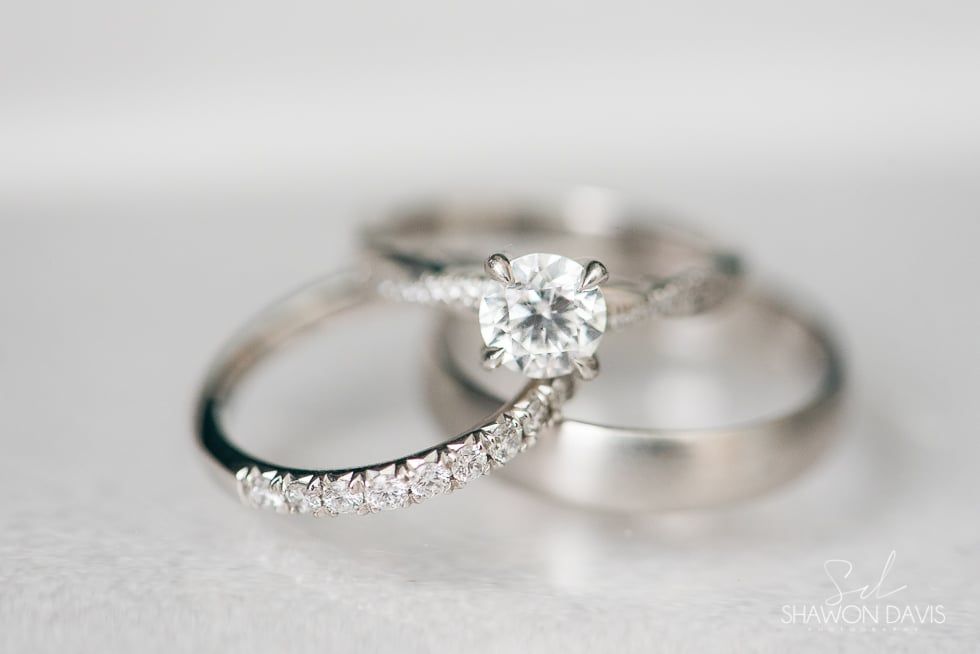 Two silver wedding rings, one with a diamond and pavé band, on a soft gray background