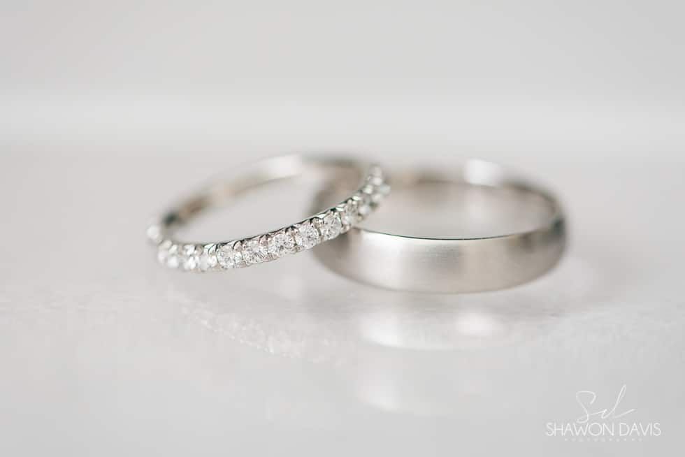 Two silver wedding rings, one plain and one diamond-studded, on a white surface