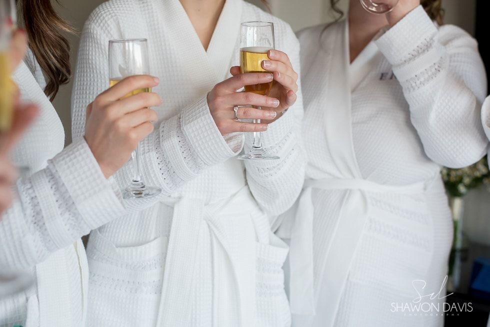 People in white robes holding champagne flutes and glasses of orange drink at a celebration
