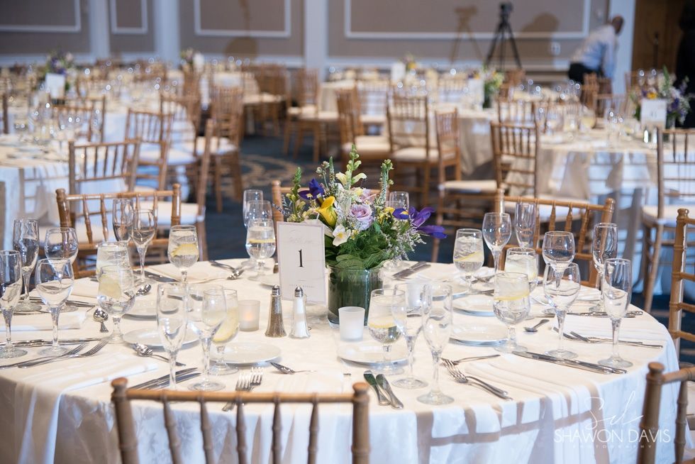 Round banquet tables set for a wedding reception with white tablecloths, glassware, and floral centerpieces