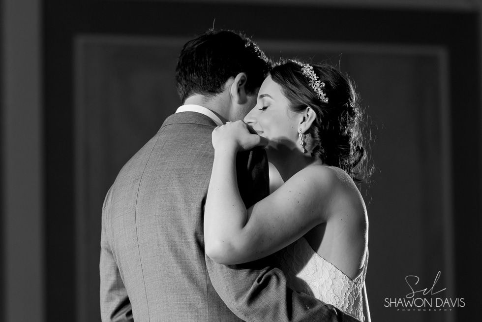 Black-and-white wedding couple embracing and smiling closely indoors