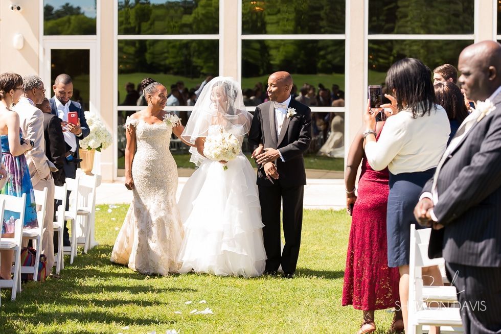 Bride and groom exchanging vows outdoors during a wedding ceremony with guests seated nearby