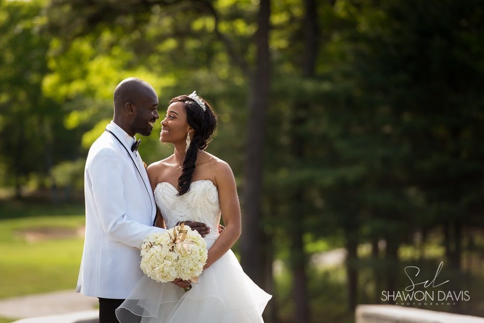 Bride and groom holding hands outdoors, smiling in a garden wedding portrait