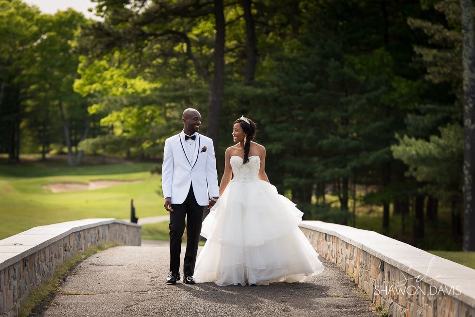 Bride and groom in formal wear walking on a stone bridge in a wooded park