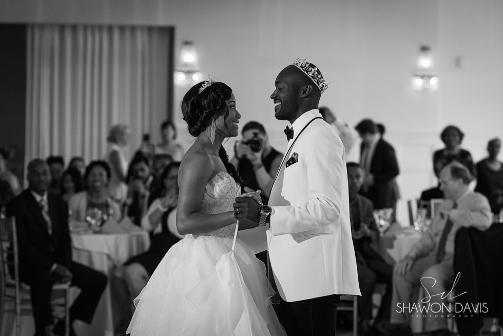 Bride and groom dance at a wedding reception, smiling and holding hands