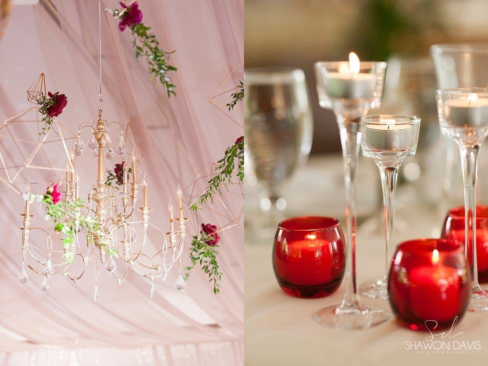 Elegant table setting with red candles, glassware, and pink floral drapery