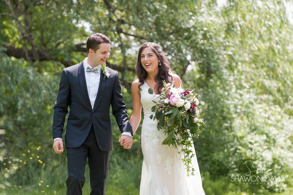 Bride and groom in wedding attire walking hand in hand in a green garden