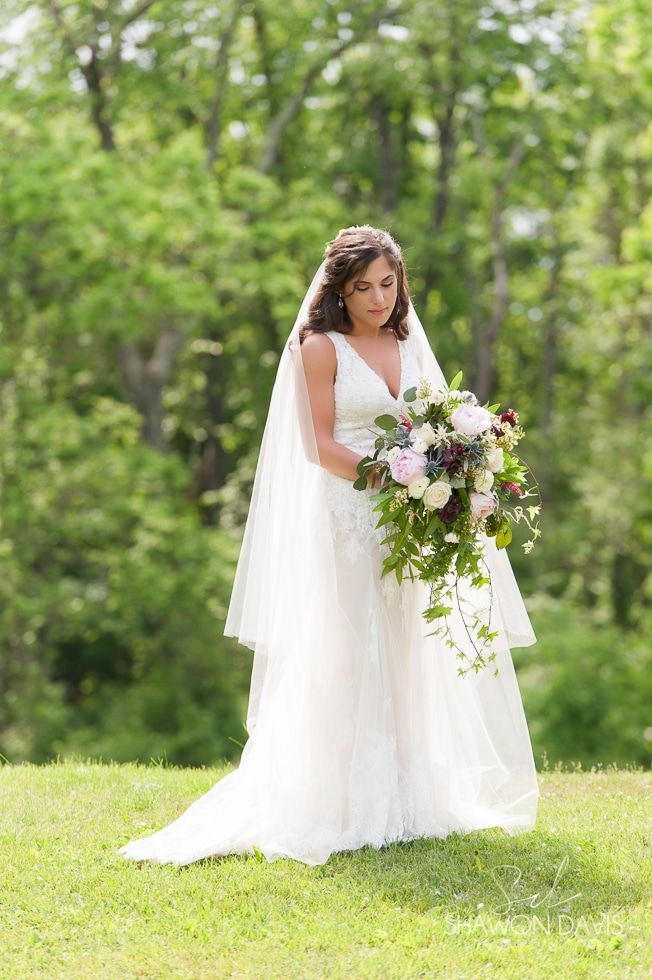 Bride in a white gown holding a bouquet in a sunlit grassy garden
