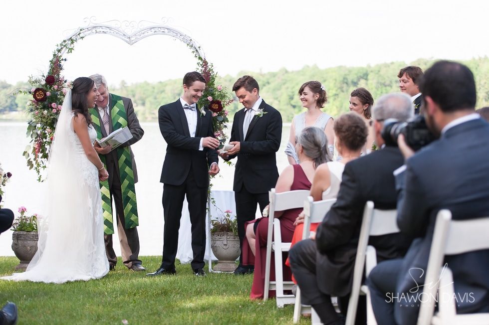 Bride and groom exchanging vows at an outdoor wedding ceremony under a heart-shaped arch