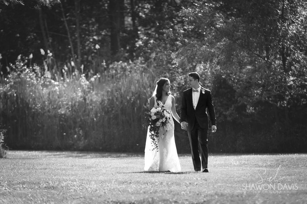 Bride and groom walking hand in hand in a black-and-white outdoor scene