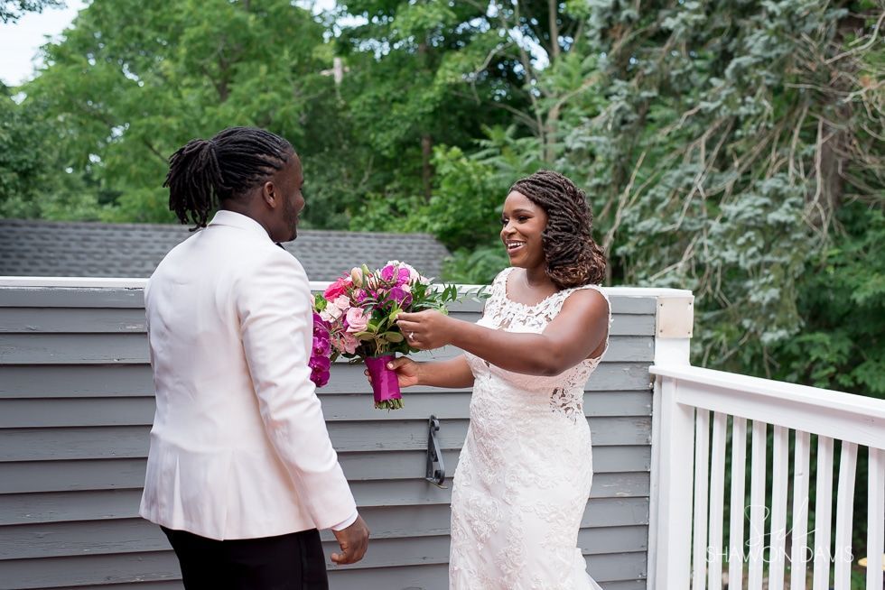 Bride holding bouquet on deck as they face each other outdoors, smiling