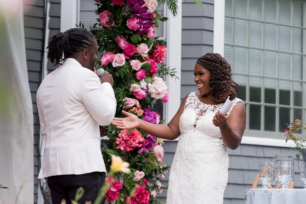 Bride and guest exchanging a hand squeeze at a wedding reception with pink floral decor