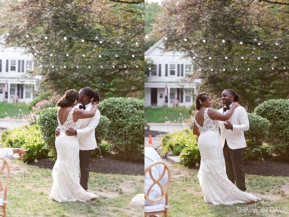 Two brides in white dresses embrace at an outdoor wedding ceremony under string lights.