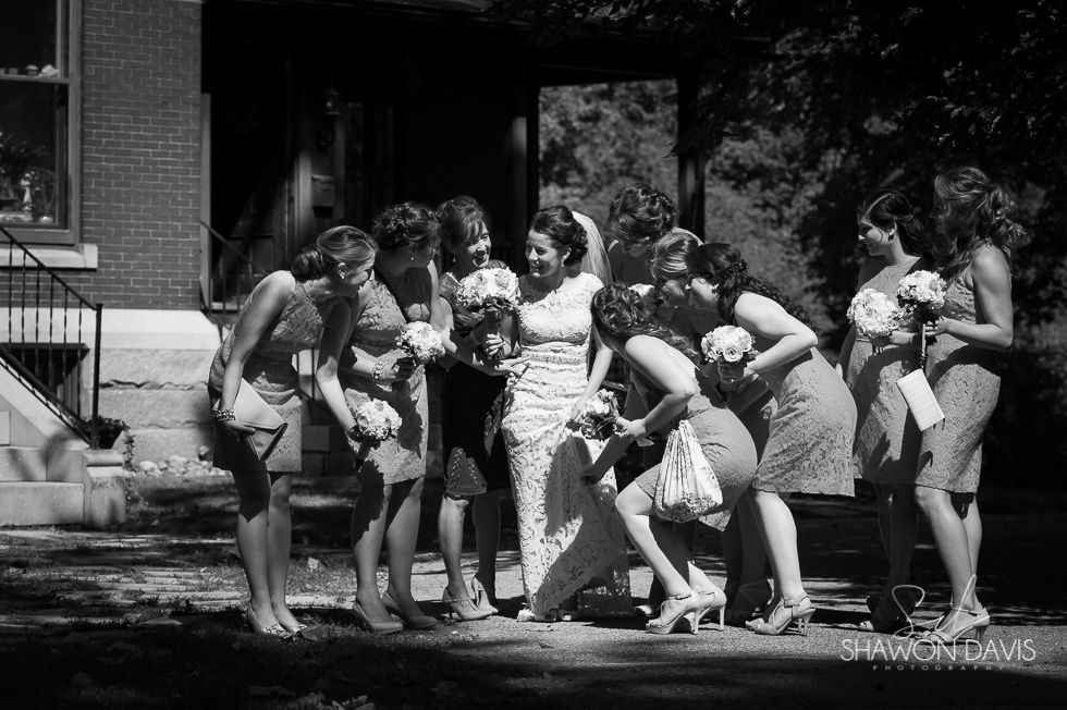 Group of people gathered outdoors around a small dog on a lawn, smiling and leaning in.
