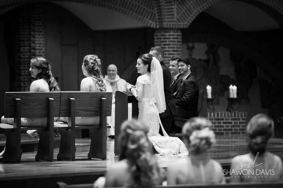Black-and-white church wedding ceremony with bride, groom, officiant, and seated guests
