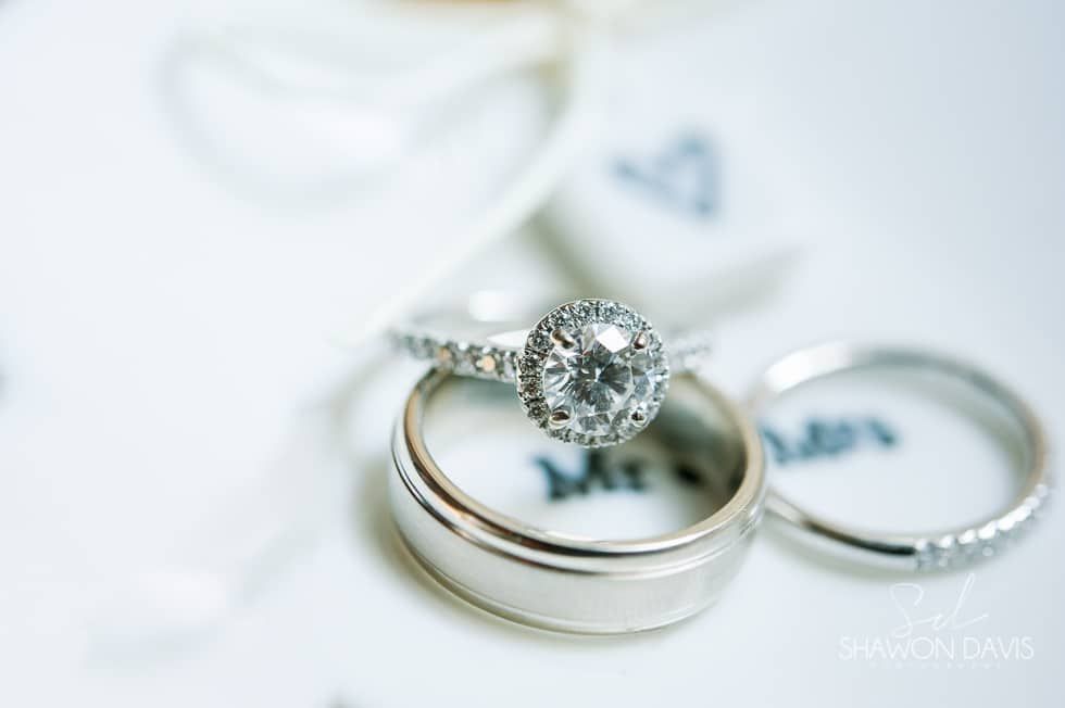 Three silver wedding rings, one with a diamond, on a white fabric background