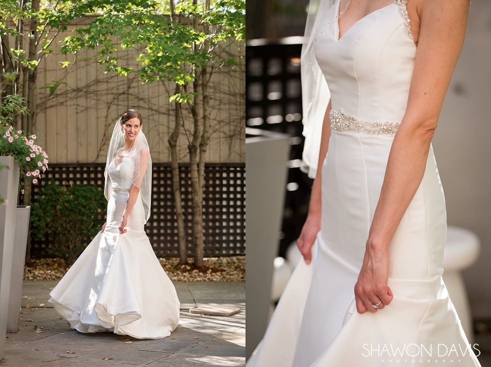 Bride in white wedding gown and veil walking outdoors near trees and a building