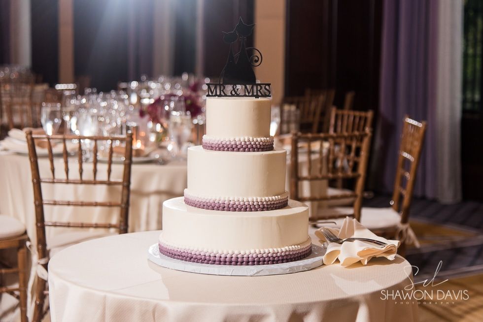Elegant white tiered wedding cake on a round table in a decorated reception hall
