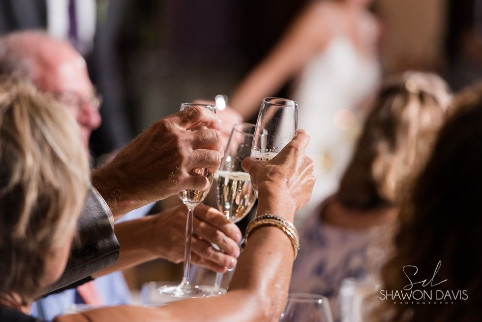 Hands raising champagne flutes at a blurred wedding reception