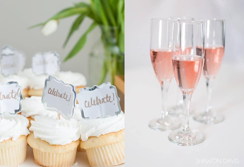 Cupcakes with white frosting and silver name tags beside three glasses of pink sparkling drink