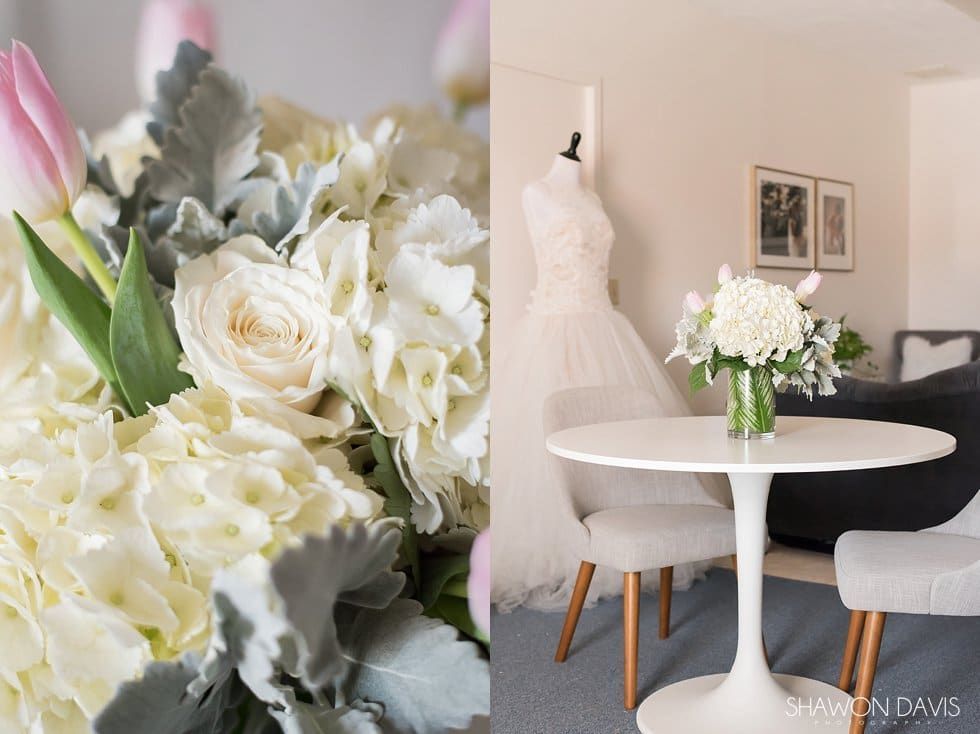 Bright floral bridal-style room with white dress, table, chairs, and large white bouquet on a wall close-up
