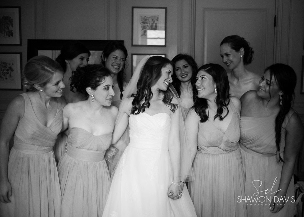 Bride with bridesmaids in matching dresses, smiling together indoors at a wedding celebration