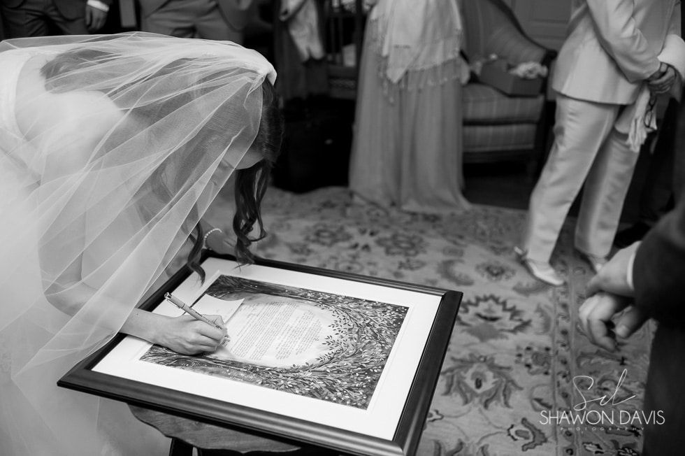 Bride signing wedding document in a formal indoor ceremony