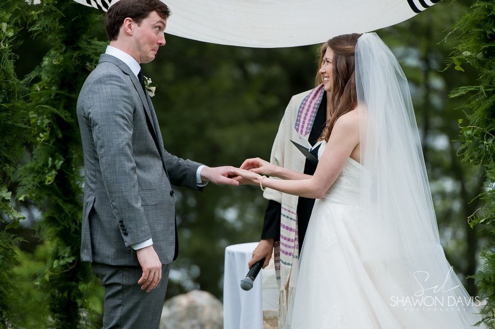 Bride and groom exchanging vows under a white canopy outdoors, holding hands during a wedding ceremony